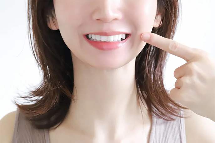 白い歯を見せる女性の口元